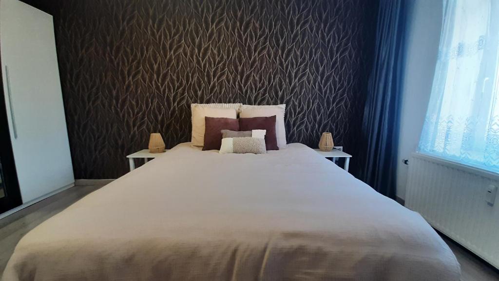 a large white bed in a bedroom with a wall at Le duo virtonnais - appartement 4 personnes au coeur de la gaume in Virton