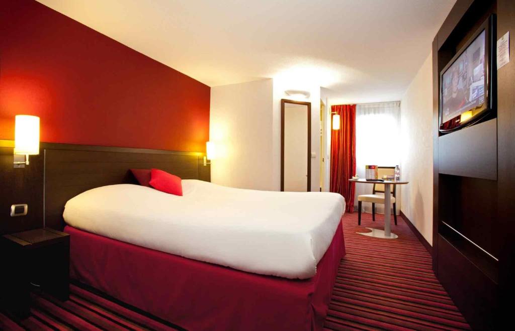 a hotel room with a large bed and a television at ibis Styles Belfort Centre in Belfort