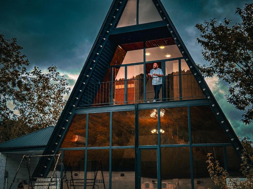 a man standing on the balcony of a glass building at Qafqaz Riverside Chalet in Gabala