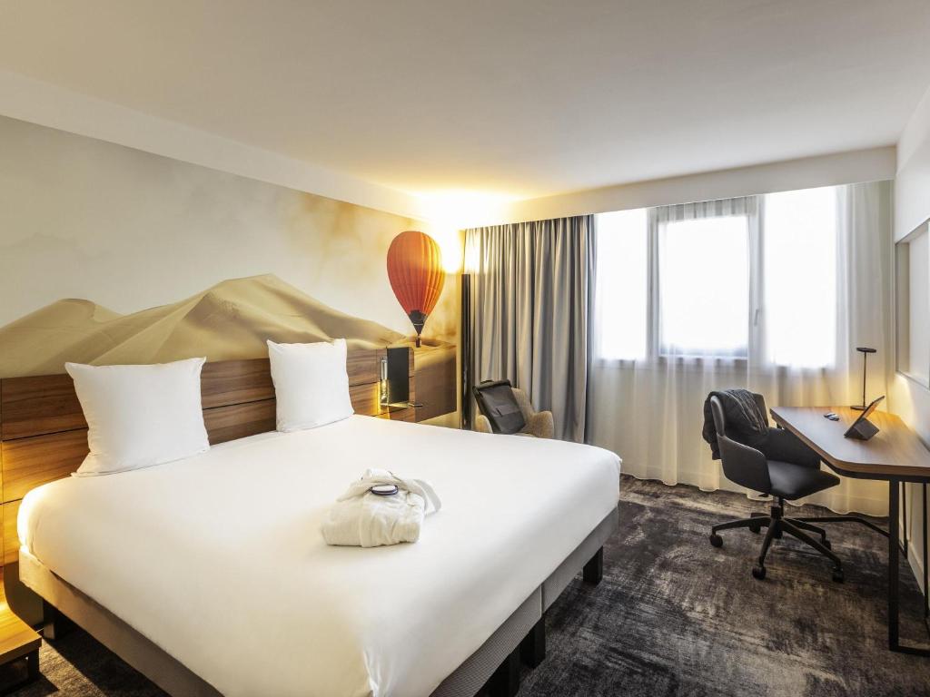 a hotel room with a large bed and a desk at Novotel Bordeaux Centre Gare Saint Jean in Bordeaux