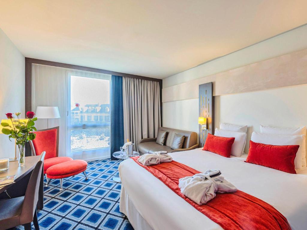 a hotel room with a large bed with red pillows at Mercure Chartres Centre Cathedrale in Chartres