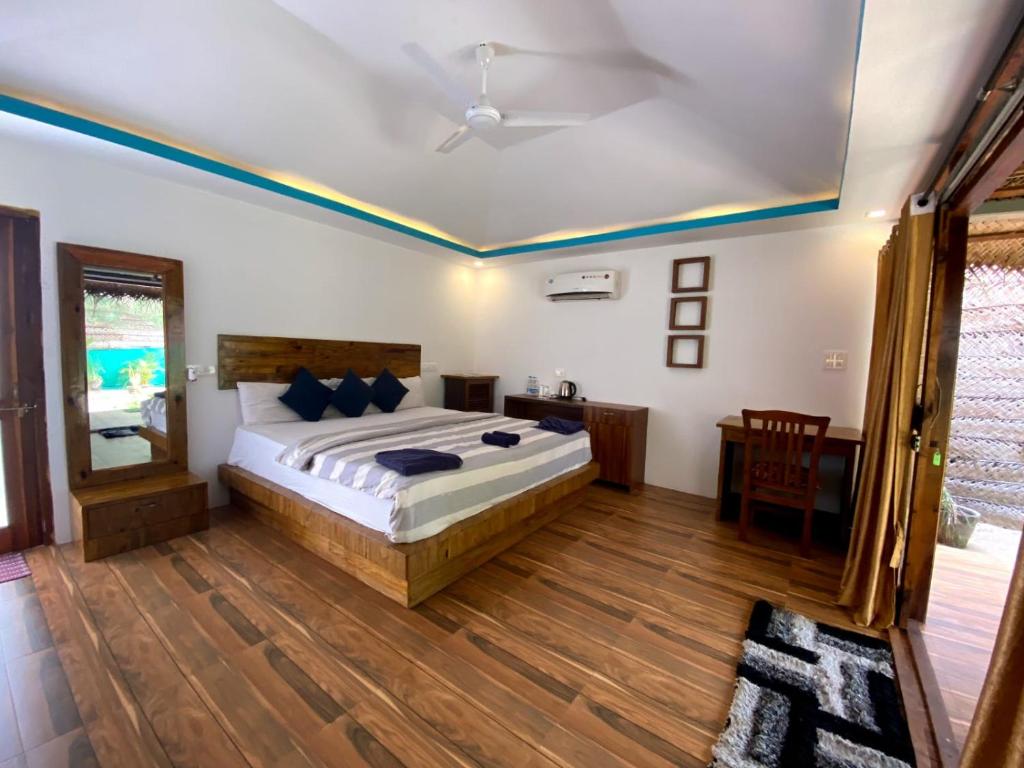 a bedroom with a large bed and a wooden floor at The Coast Beach Resort in Agonda