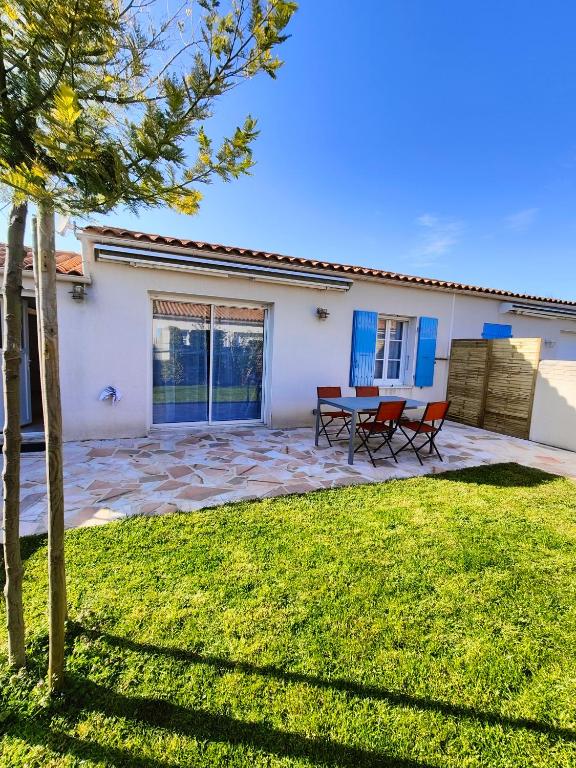 een huis met twee stoelen en een tafel in een tuin bij Oléron proche plage pour vacances ou travail in Dolus d'Oléron
