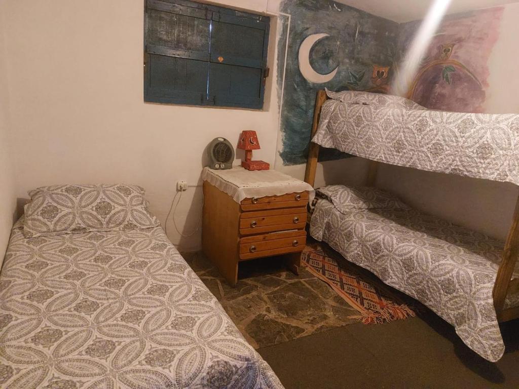 a bedroom with two bunk beds and a night stand at Hostel Kuku in Mina Clavero