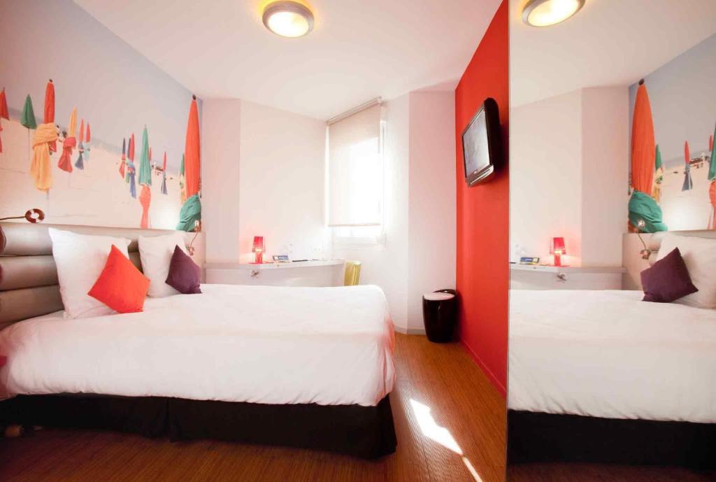 a hotel room with two beds and a tv at ibis Styles Saint Brieuc Gare Centre in Saint-Brieuc