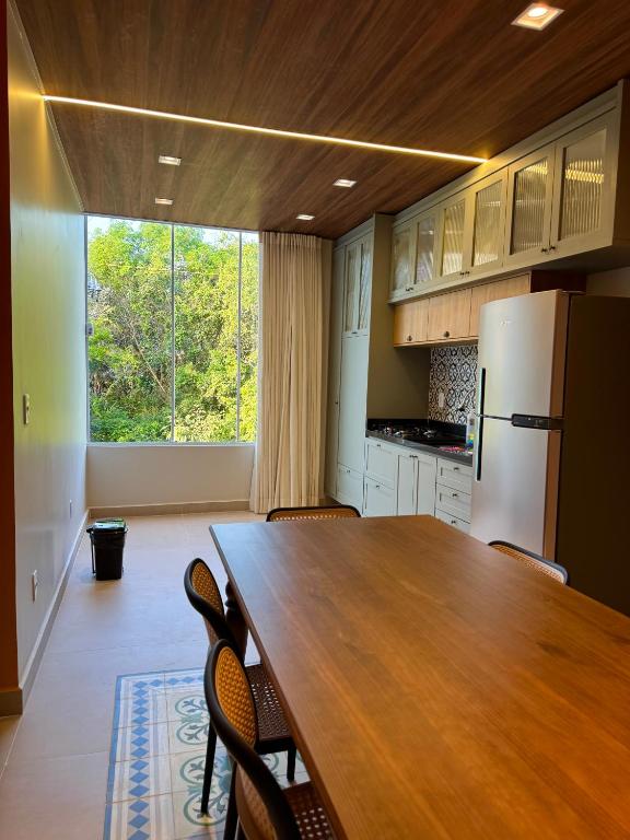 a kitchen with a wooden table and a refrigerator at Ilha Bela Alter do chão - Apartment 2 suites in Santarém