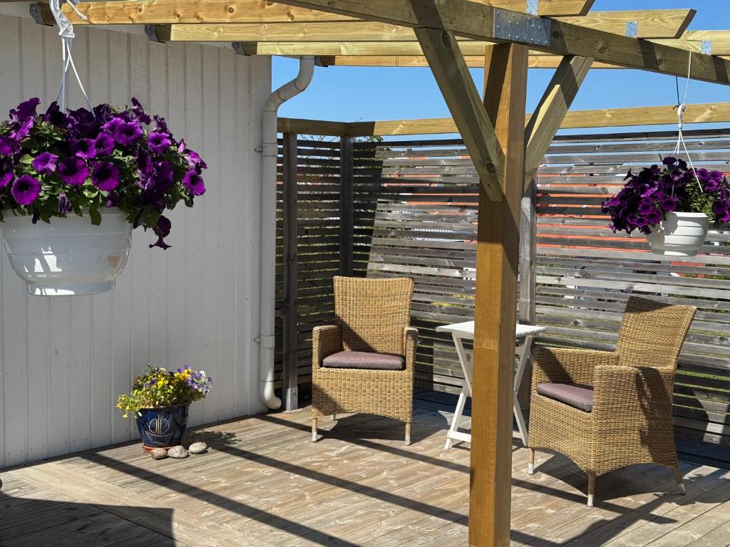 a patio with chairs and a pergola with purple flowers at Sussi`s Guesthouse in Kungshamn