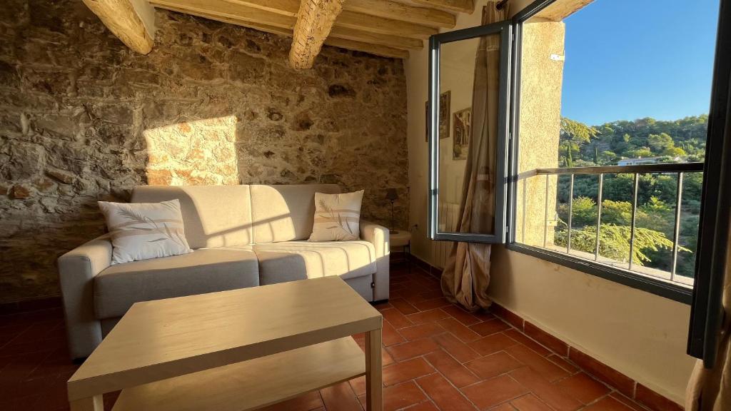 a living room with a couch and a table and a window at Au puits de Figa in Figanières