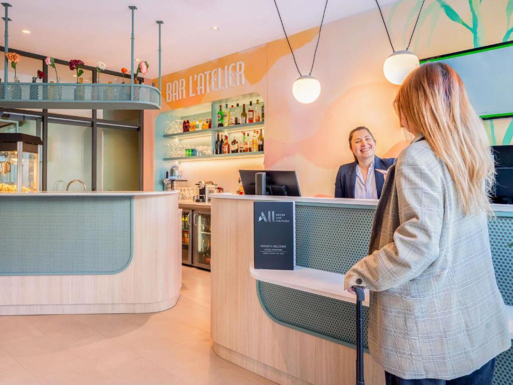 モンルージュにあるイビス スタイルズ パリ ポルト ドルレアンの店のカウンターに立っている女性