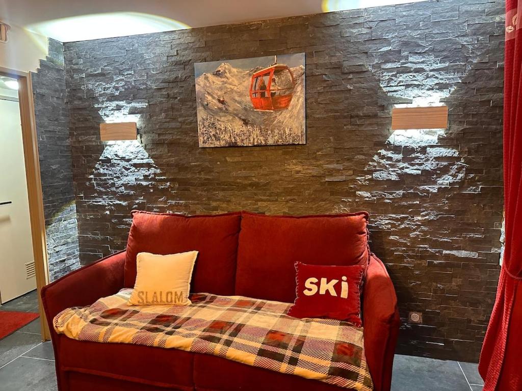 ein rotes Sofa mit zwei Kissen an einer Wand in der Unterkunft Appartement au pied des pistes Serre chevalier in La Salle Les Alpes