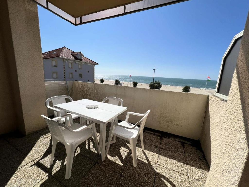 einen Tisch und Stühle auf einem Balkon mit Blick auf den Strand in der Unterkunft Résidence Cap Atlantic - 024 - Appartement avec belle terrasse et vue imprenable sur l'Océan MAE-1951 in Soulac-sur-Mer