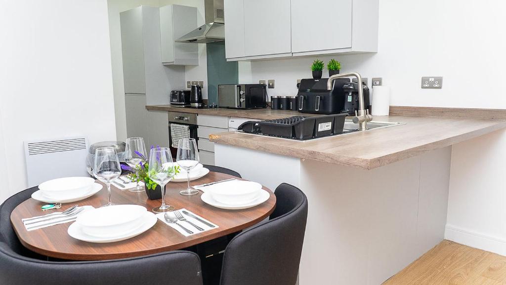 Una cocina con una mesa de madera con sillas y una encimera. en 2 Bed Deluxe Apt City Centre, Long stay, en Mánchester