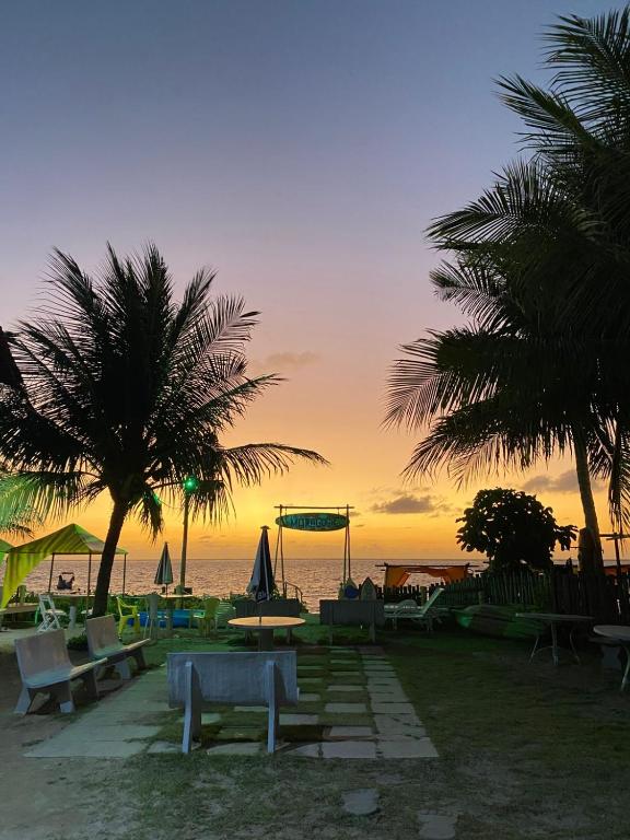 a beach with palm trees and a playground at sunset at Casa a beira Mar - Ponta de Mangue - Maragogi in Maragogi