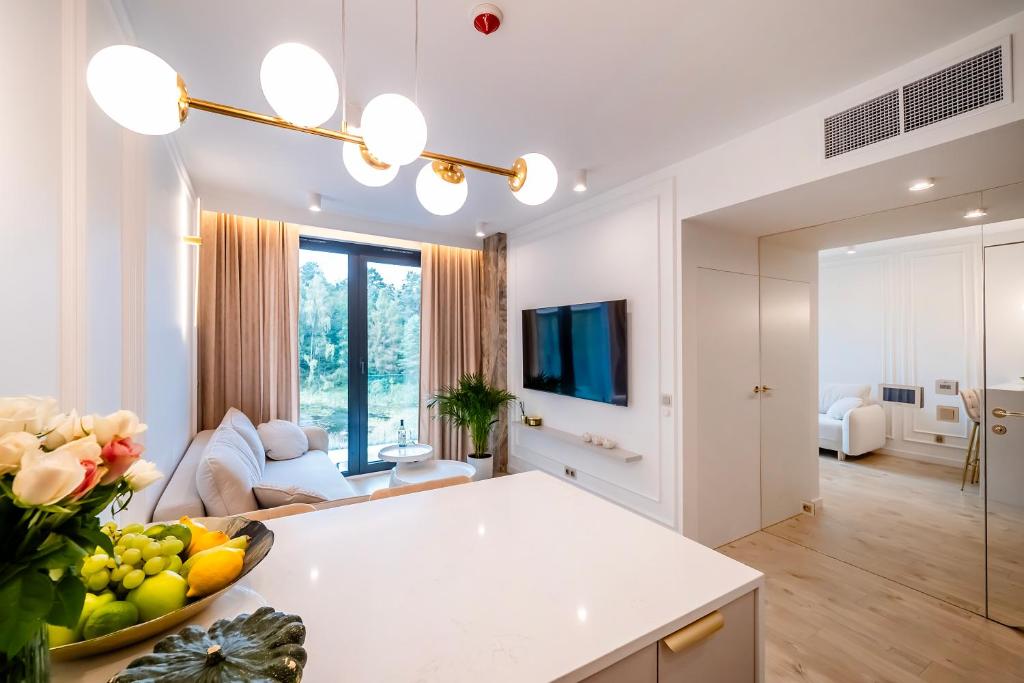a white living room with a table and a couch at Vidok 201 in Olsztyn