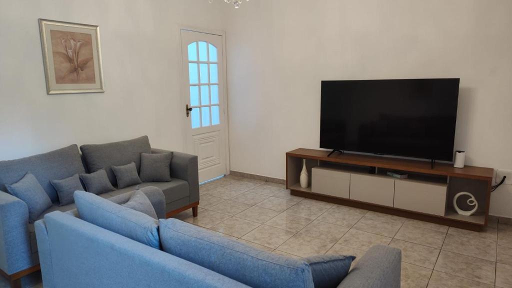 a living room with two blue couches and a flat screen tv at Casa no Centro de São Roque - SP in São Roque