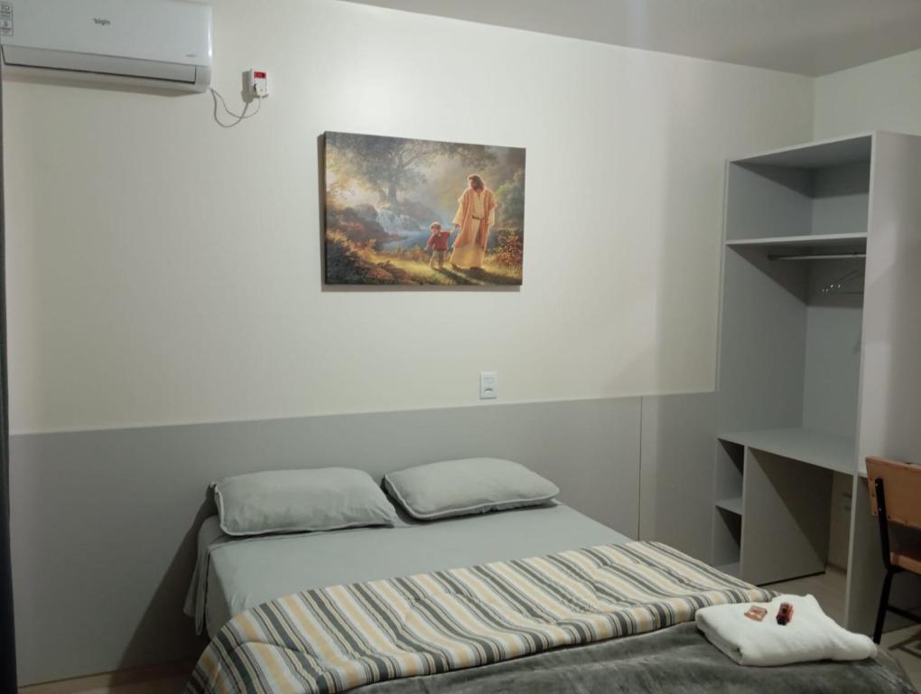 een slaapkamer met een bed en een schilderij aan de muur bij Pousada & Hospedaria Monte Tabor in Francisco Beltrão