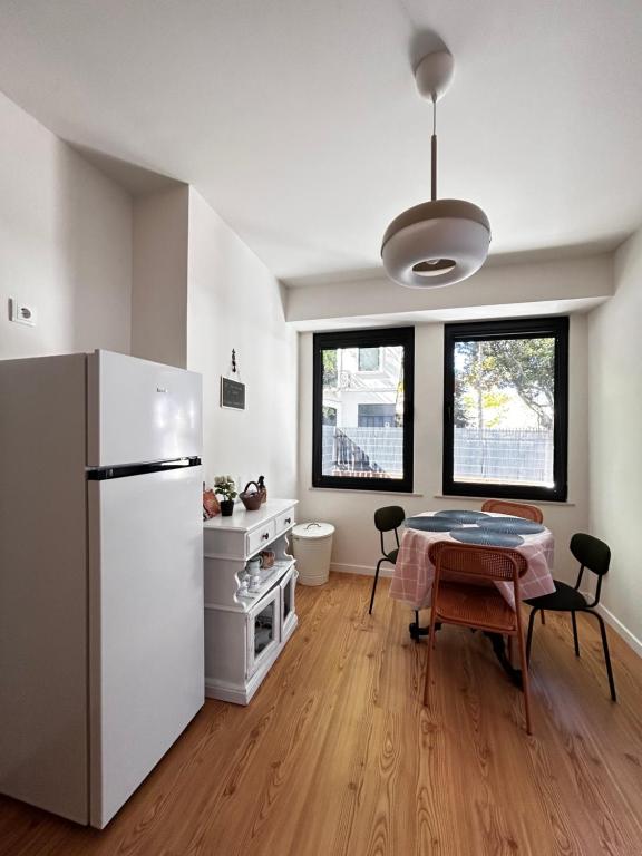 Una cocina con una mesa y un refrigerador blanco. en Cobalto 2 Quartos Parque Cidade Pet Friendly, en Aveiro