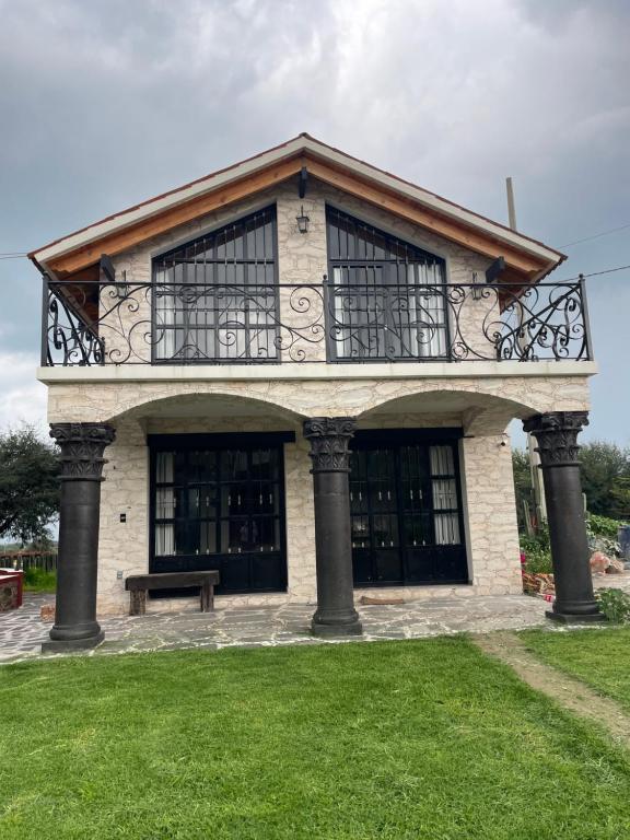 ベルナルにあるCabañas La Rinconada, Bernalのバルコニーと芝生のベンチがある建物