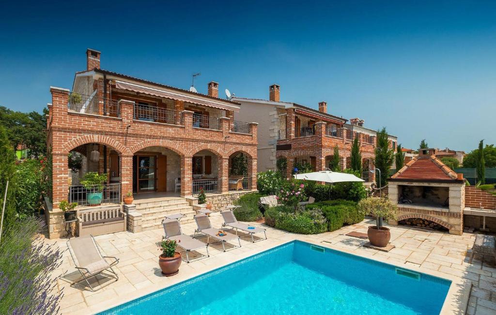 une grande maison en briques avec une piscine en face de celle-ci dans l'établissement Lovely Home In Kastelir, à Kaštelir