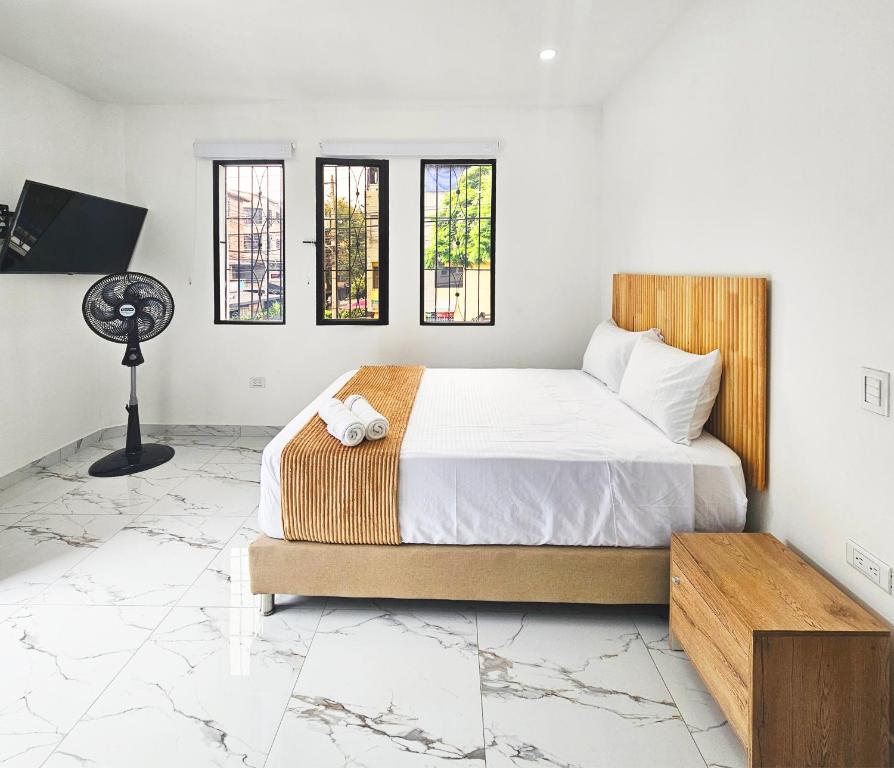 a bedroom with a bed with white sheets and windows at Casa Eterna Campo Valdés in Medellín