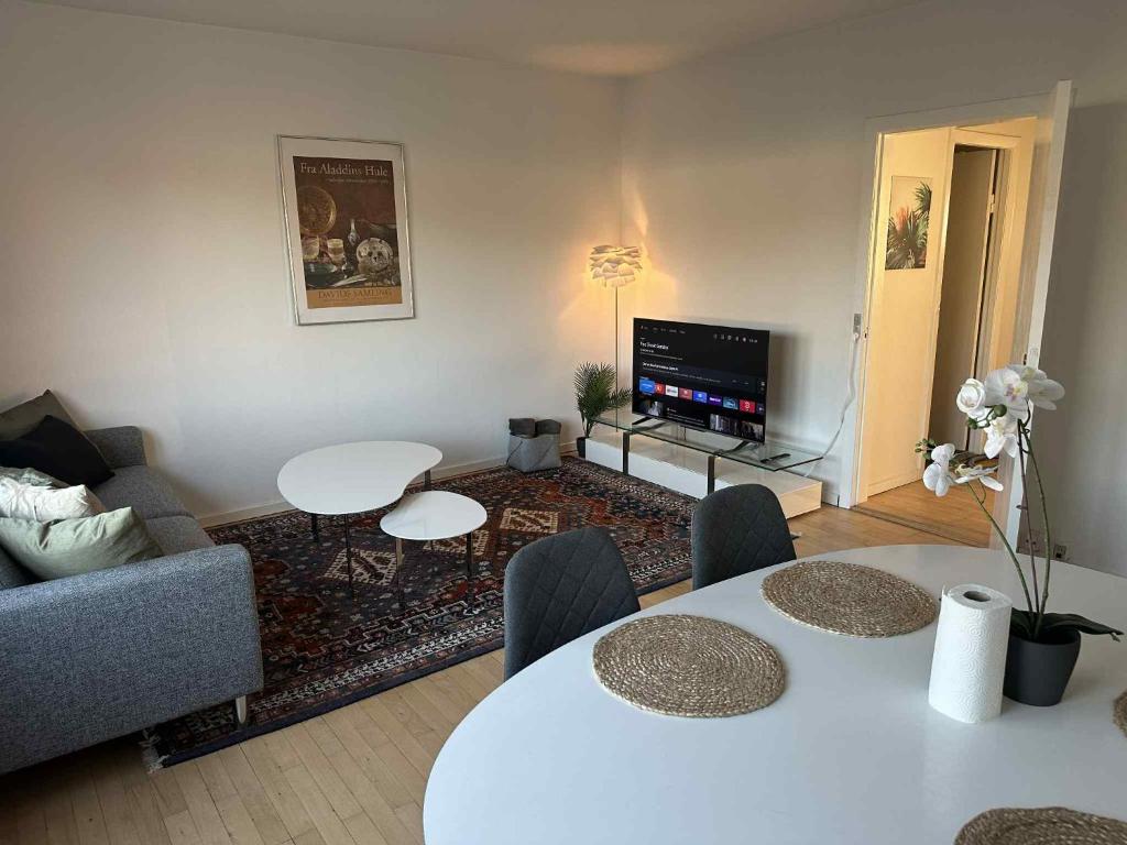 a living room with a table and chairs and a tv at Bright & cozy city apartment in Hvidovre