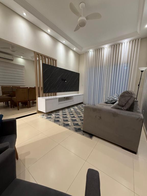 a living room with a couch and a flat screen tv at Sua casa em Orlândia in Orlândia