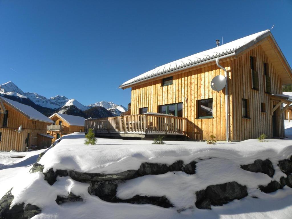 a log cabin in the snow with mountains in the background at Das Edelweiss in Hohentauern