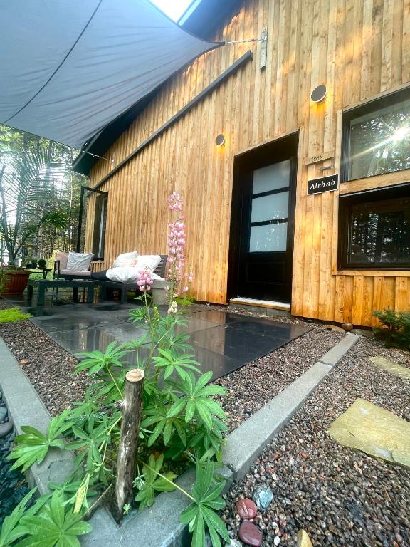 a wooden building with a patio with a table and flowers at Le 1040 St-Mathieu du Parc in Saint Mathieu Du Parc