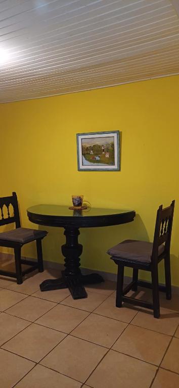 a table and chairs in a room with a yellow wall at Pukará Lodge in Colonia del Sacramento