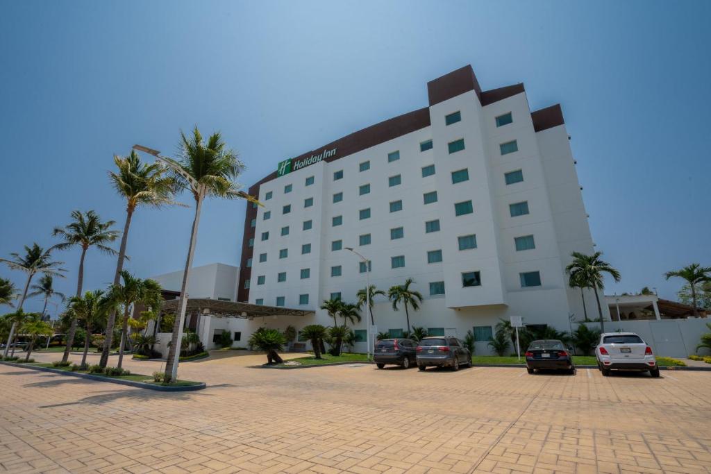 a large building with cars parked in a parking lot at Holiday Inn Acapulco La Isla by IHG in Acapulco