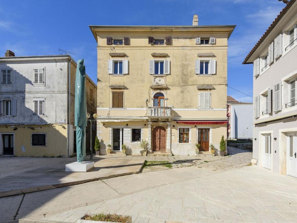 a large tan building with a balcony in a courtyard at Urban Loft Marafor Porec in Poreč