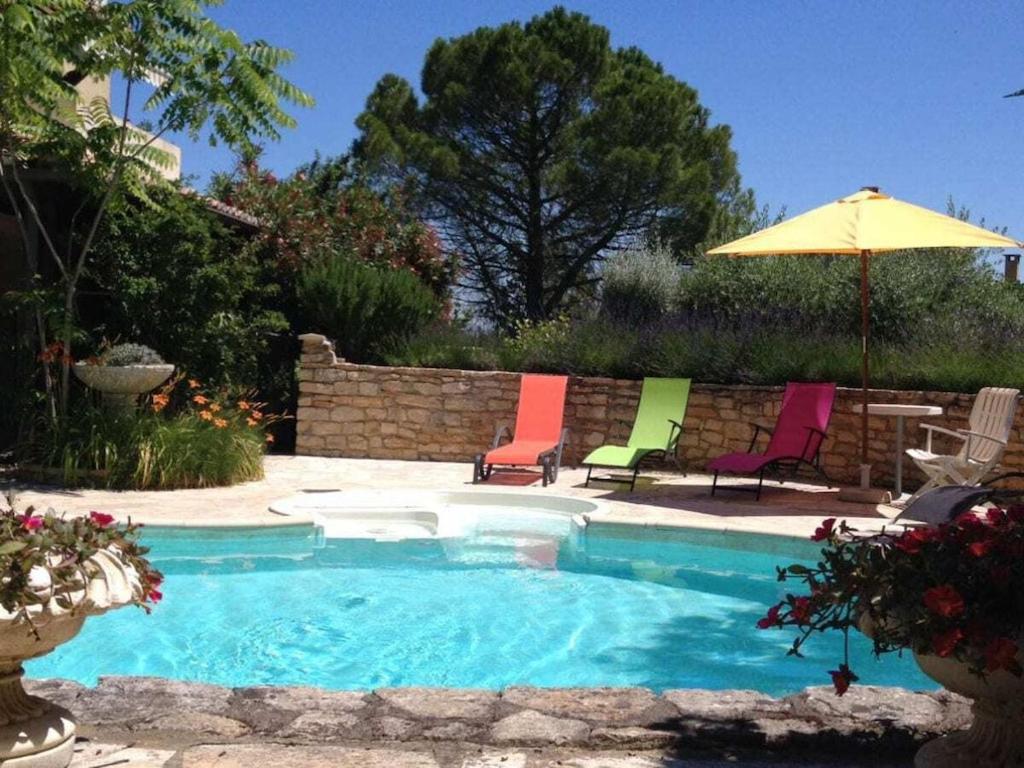 a swimming pool with chairs and an umbrella at in southern France La Bastide in Saint-Julien-de-Peyrolas