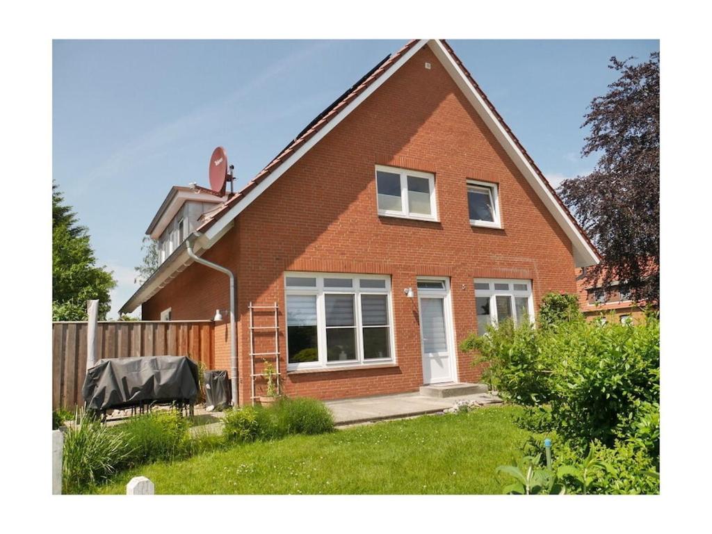 a red brick house with a fence in the yard at Holiday apartment with 2 bedrooms in Hohenfelde
