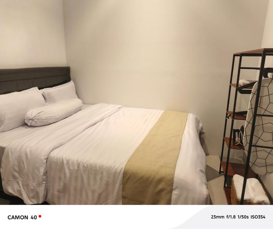 a bedroom with a bed with white sheets and a shelf at CBD Studio Loft 1B at City Center! in Medan