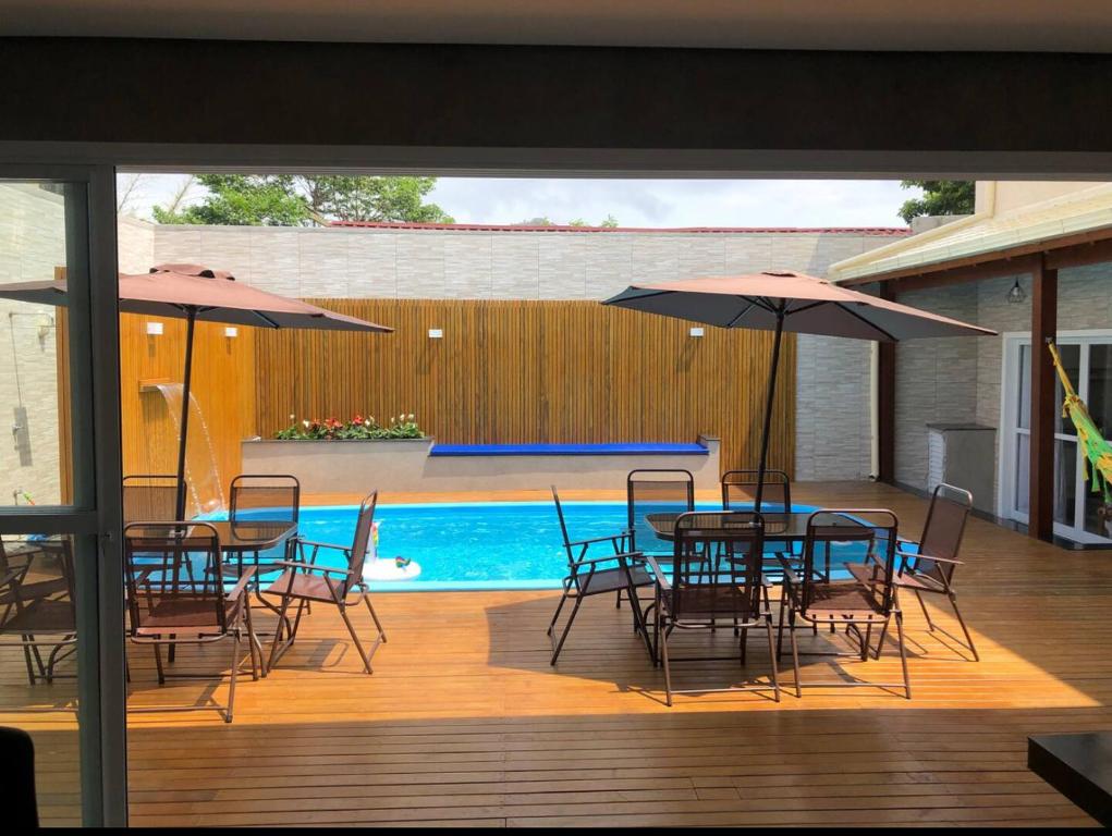 een patio met tafels en stoelen, parasols en een zwembad bij Casa com 4 quartos com piscina próximo da praia do campeche in Florianópolis