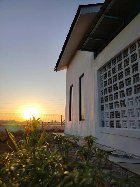a building with the sunset in the background at Saya & Awak Tiny House in Kota Bharu