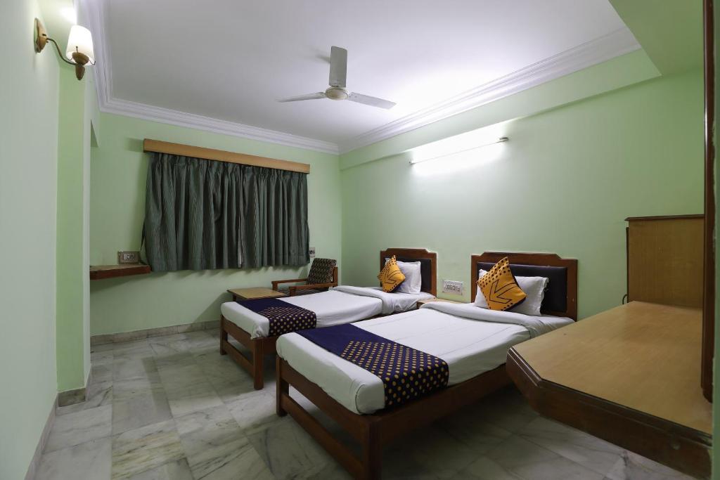 Dos camas en una habitación con paredes verdes. en SPOT ON Hotel Hilltop, en Vadodara