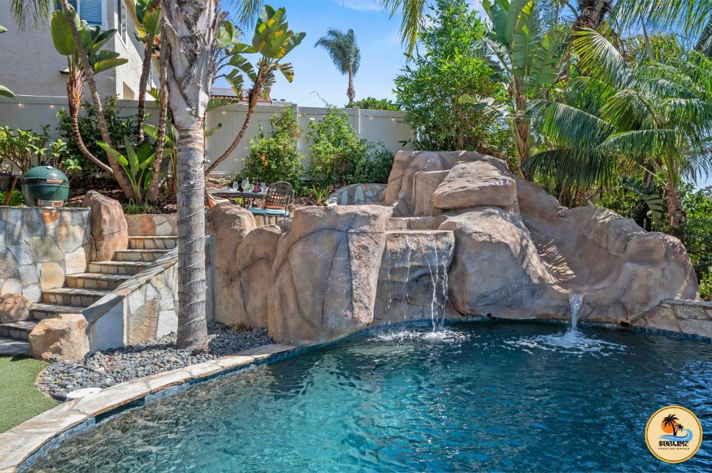 a swimming pool with a waterfall in a backyard at Slide into Paradise, Pool, Spa & Stunning Views in San Diego