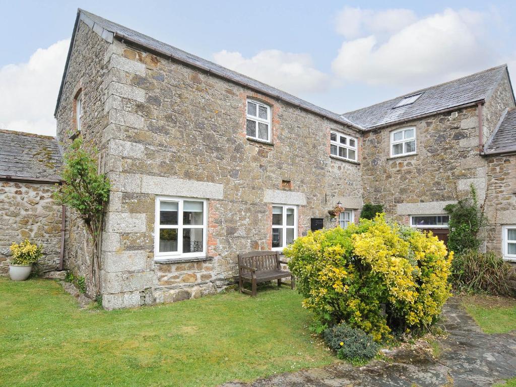 an old stone house with a bench in the yard at The Granary in Saint Minver