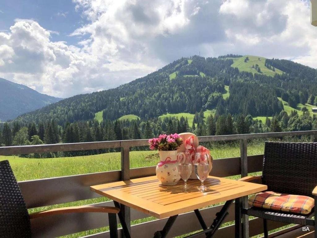 a table with two glasses and flowers on a balcony at One-bedroom apartment in Balderschwang