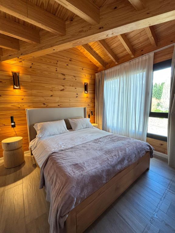 a bedroom with a large bed in a wooden room at Chapelco Golf Lodge - Depto en Aldea del Golf H6 13E in San Martín de los Andes