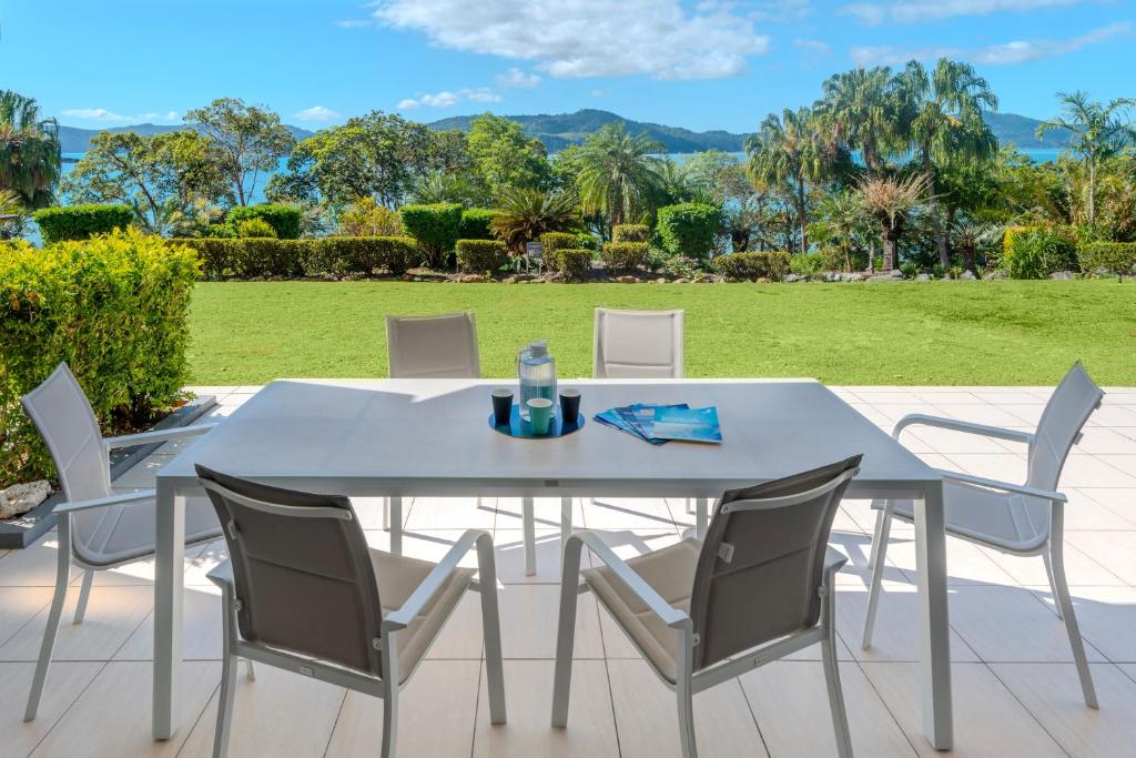a white dining table and chairs on a patio at Lagoon 004 by HamoRent on Hamilton Island in Hamilton Island