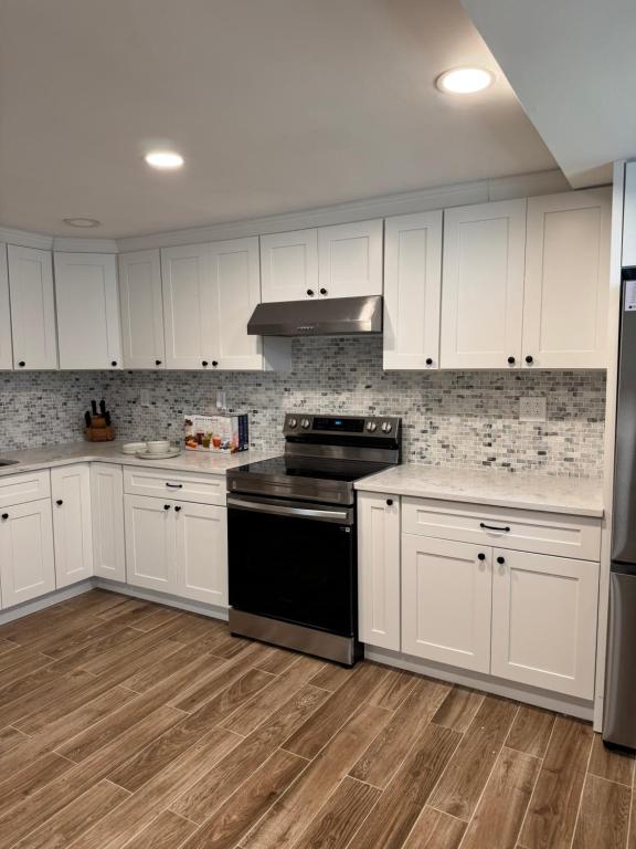 a kitchen with white cabinets and a black stove at Calm Retreat in Plainview