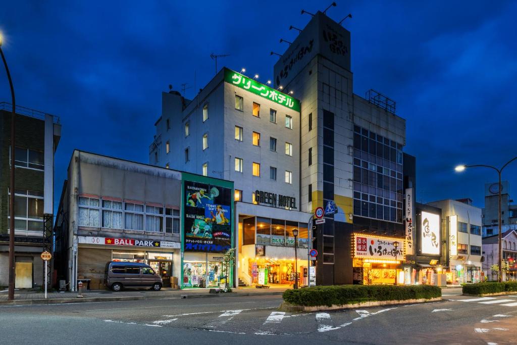 a building with a sign on it on a street at Mizusawa Green Hotel in Oshu