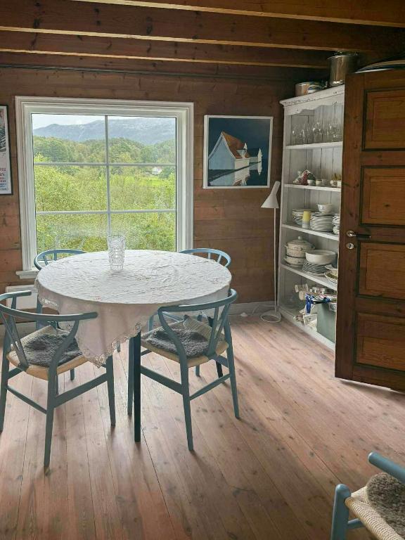 a dining room with a table and chairs and a window at Traditional Cabin With Fjord Views In Skjoldastraumen in Skjoldastraumen