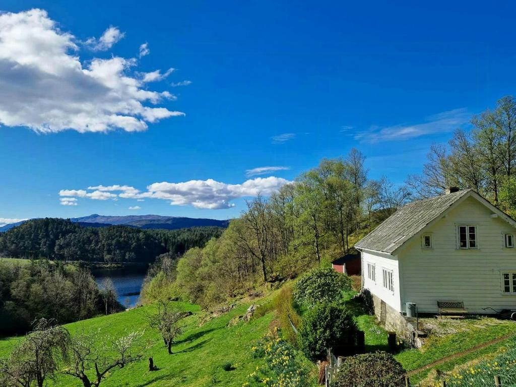 ein altes Haus auf einem Hügel neben einem Fluss in der Unterkunft Family Cabin By The Fjord In Tysnes in Uggdalseidet