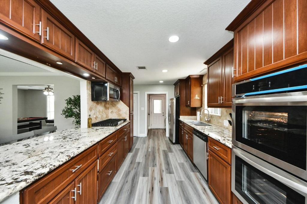 a large kitchen with wooden cabinets and marble counter tops at 4-BR Family Retreat in Quiet Conroe Neighborhood in Conroe