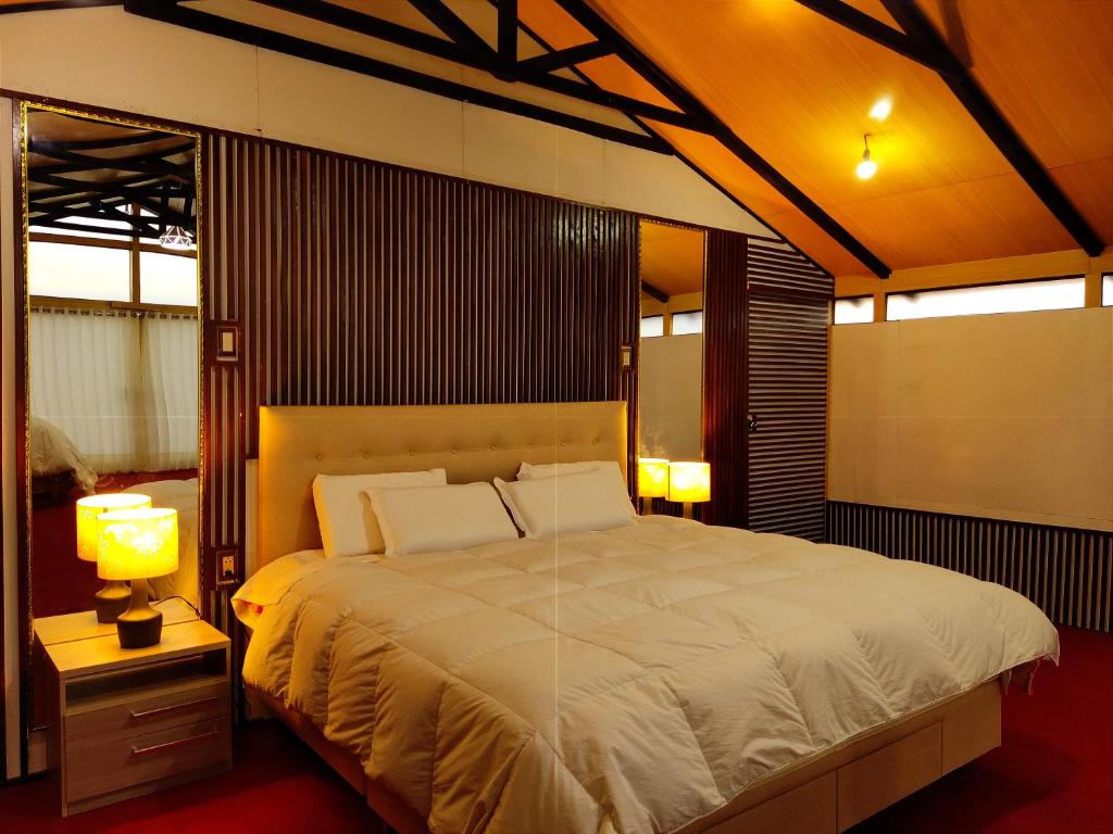 kantuta Lodge Uros في بونو: غرفة نوم بسرير كبير ومصباحين