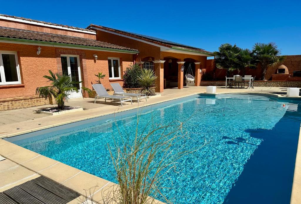 a swimming pool in front of a house at L'Hacienda Soléa in Culmont