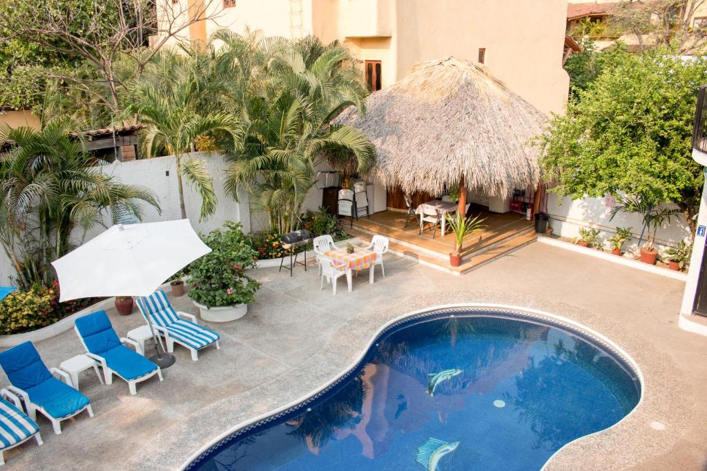 an outdoor swimming pool with chairs and a umbrella at Villas Mercedes in Zihuatanejo